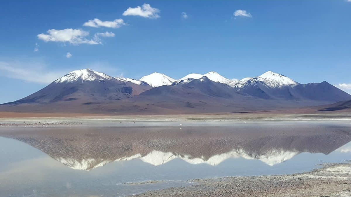 Un panorama des montagnes et des lagunes du Salar d'Uyuni, avec un magnifique reflet des montagnes sur l'eau pendant un road trip