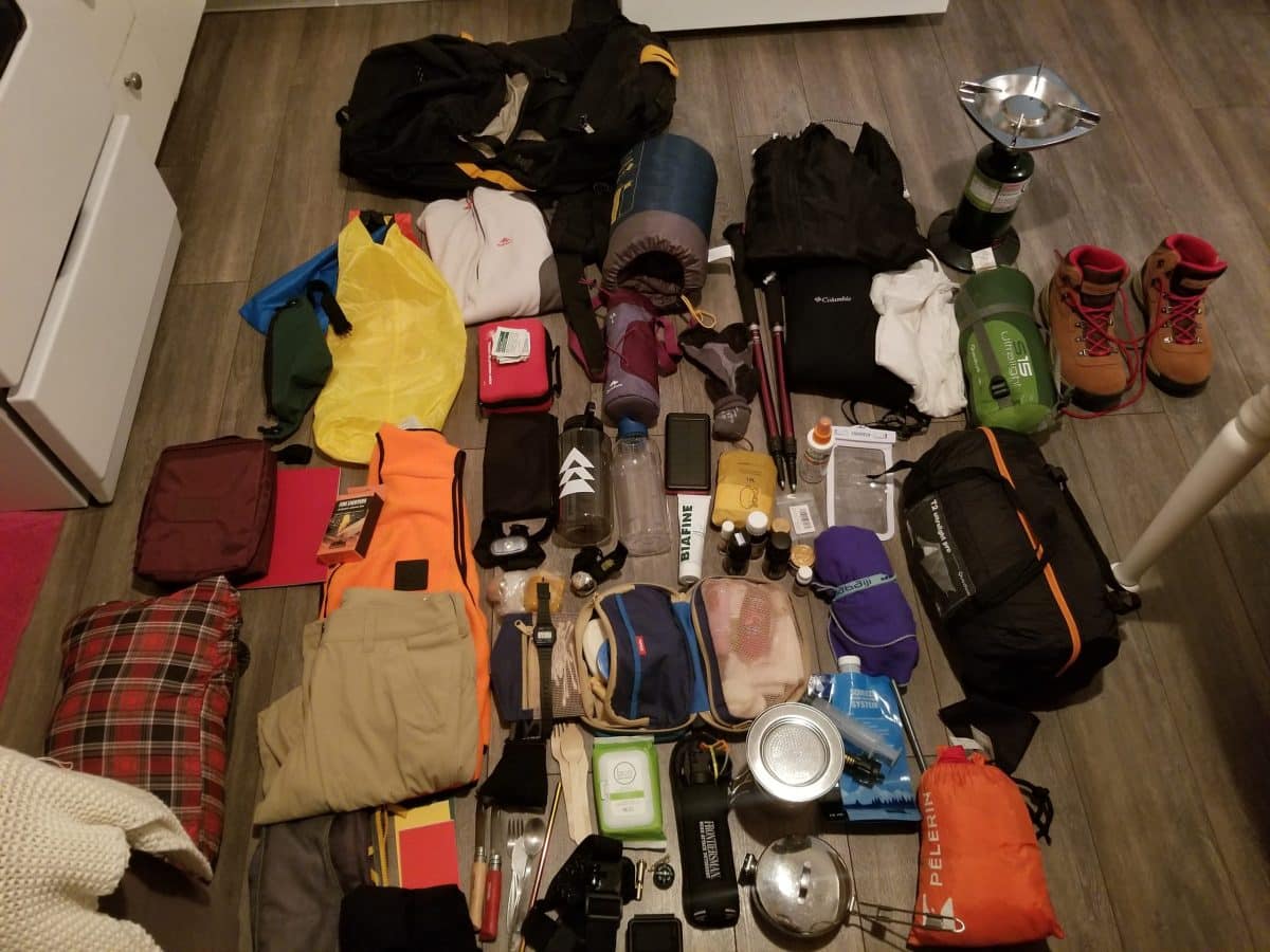 Équipement SIA organisé au sol, montrant tout le matériel de trek, y compris des bâtons, des chaussures, une trousse de pharmacie et d'autres accessoires