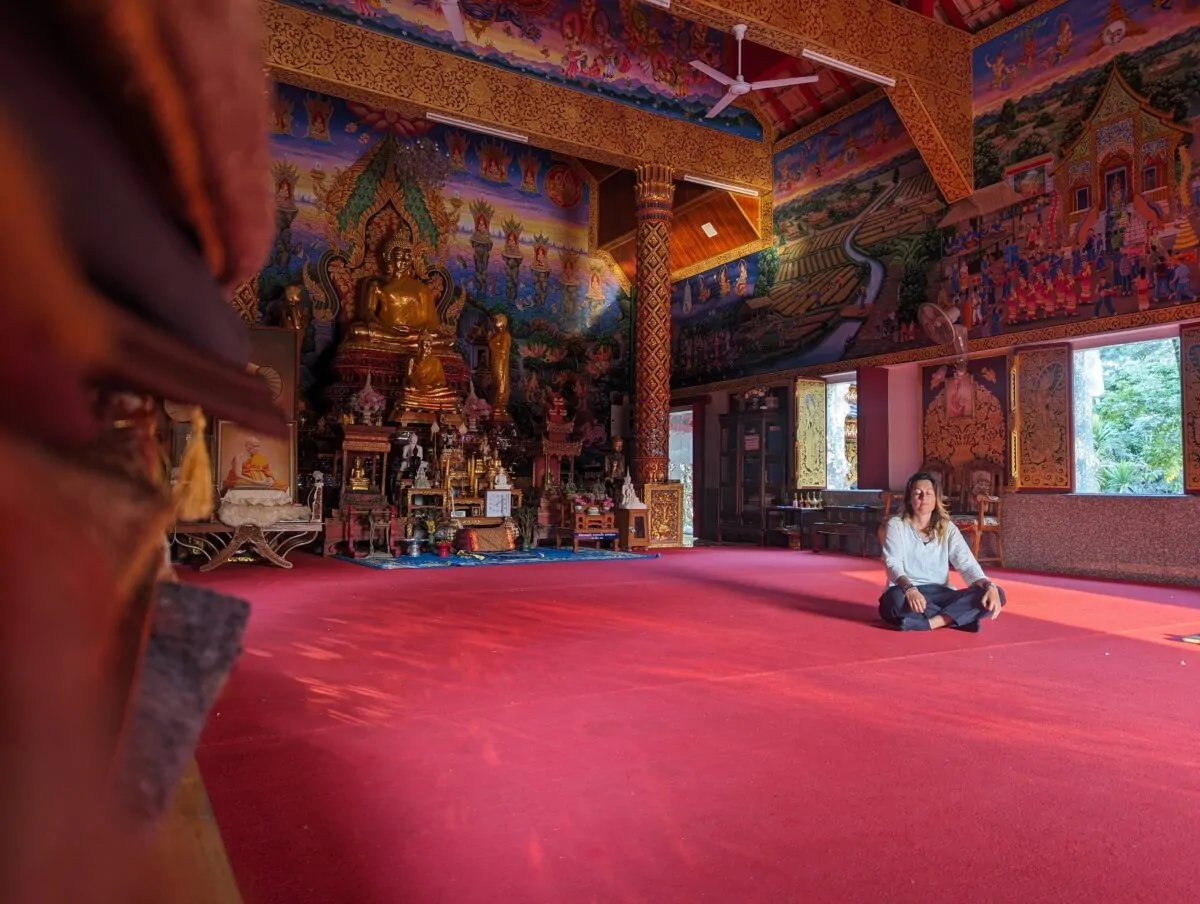 Inès en méditation en tailleur, yeux fermés, dans une salle de retraite Vipassana à Chiang Maï, Thaïlande. Atmosphère calme