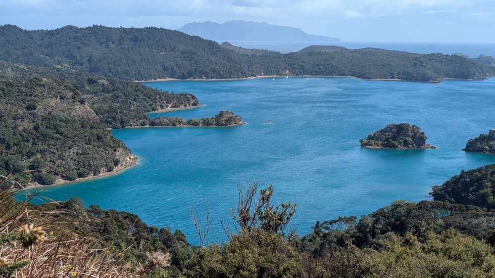 Photo d'une baie sur l'île de la Grande Barrière, avec des rochers et de l'eau bleu profond