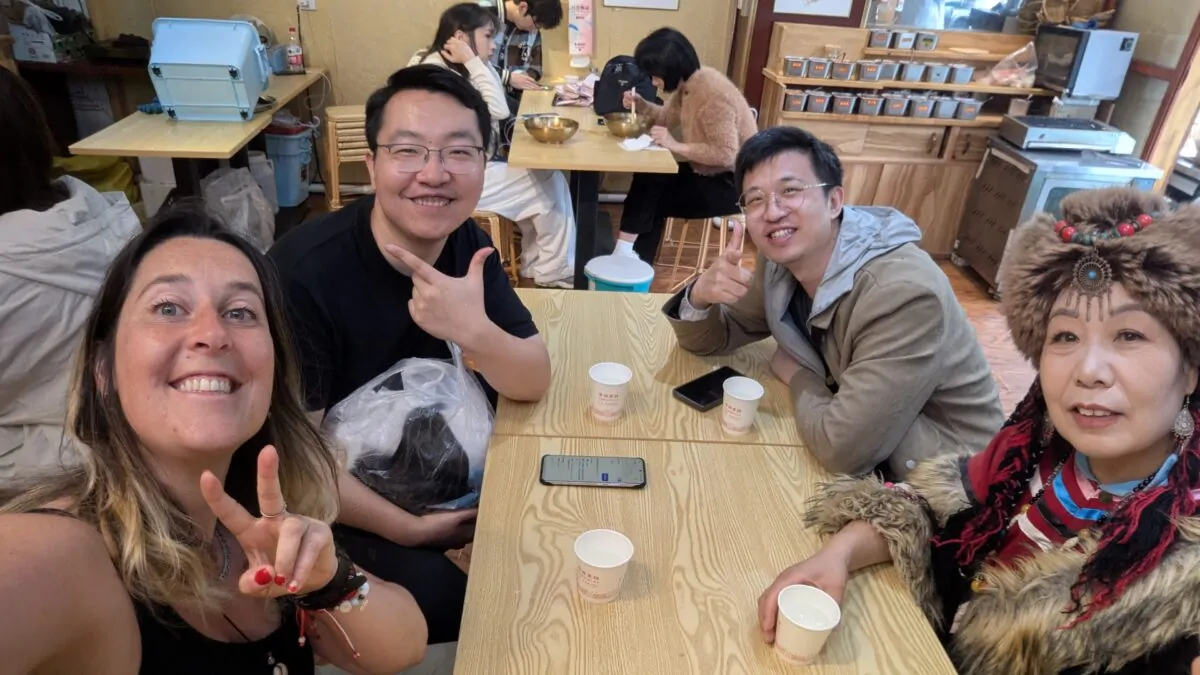 Inès entourée de quatre amis chinois autour d’une table, partage et sourires. Ambiance conviviale et chaleureuse, instant de vie quotidienne en Chine
