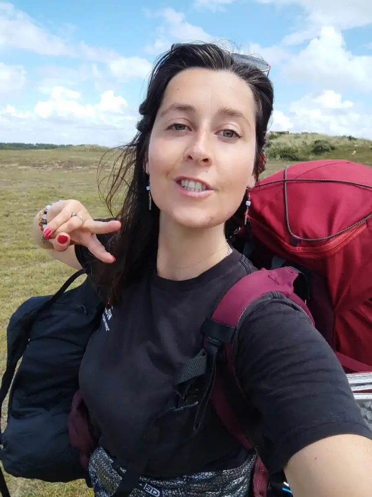 Selfie d’Inès lors d’un trek sur le sentier GR21 en Normandie, avec un paysage naturel en arrière-plan