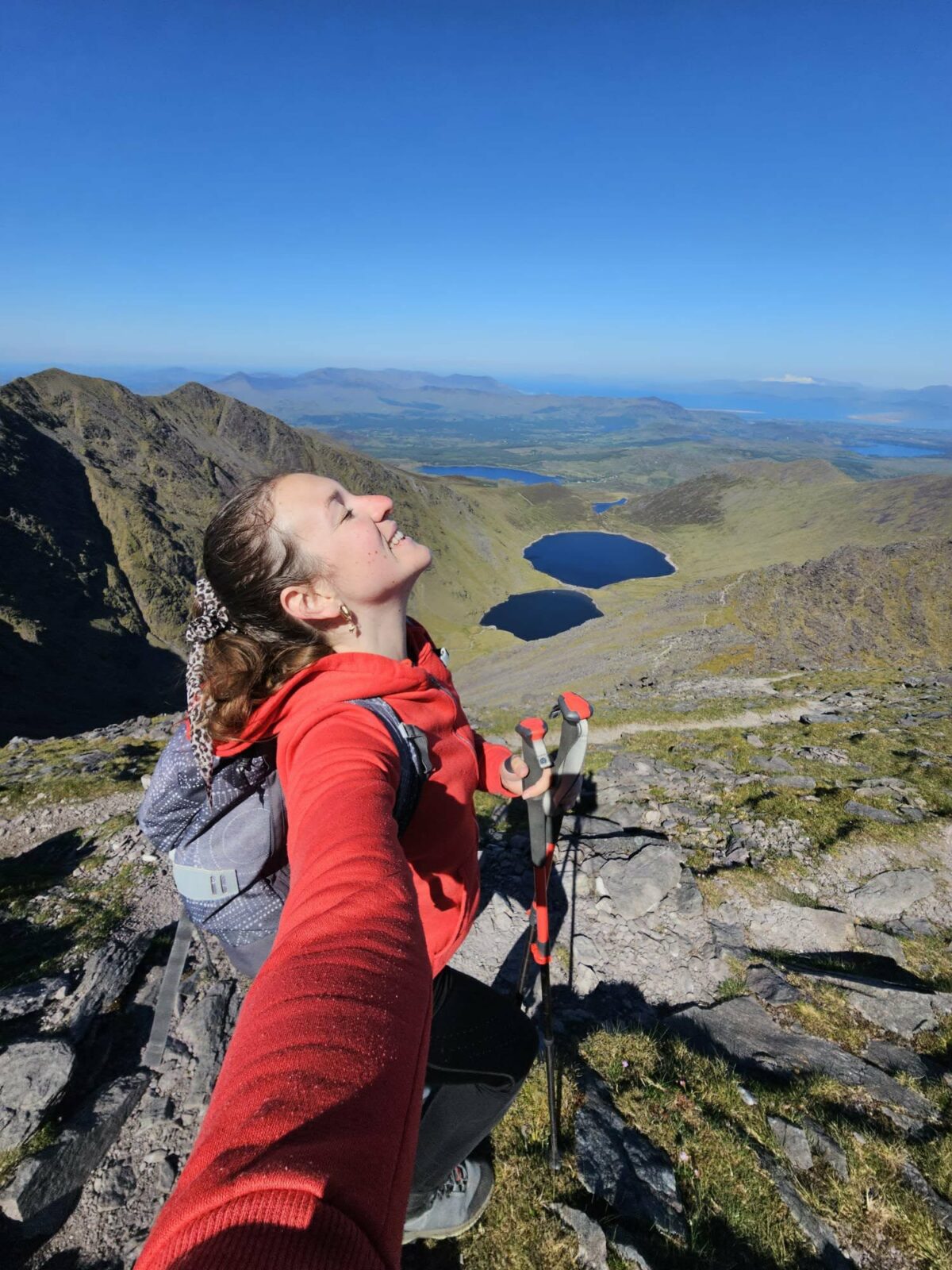 Fanny souriante et détendue au sommet d’une montagne, profitant d’un panorama lors de ses randonnées en Irlande et en Asie du Sud-Est. Illustration qui capture la liberté, l’aventure et l’émerveillement du voyage solo en pleine nature