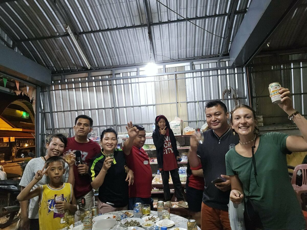 Fanny et plusieurs personnes debout autour d’une table, lors de ses voyages en Irlande et en Asie du Sud-Est. Illustration qui capture la convivialité, les échanges et le partage lors d’un moment collectif