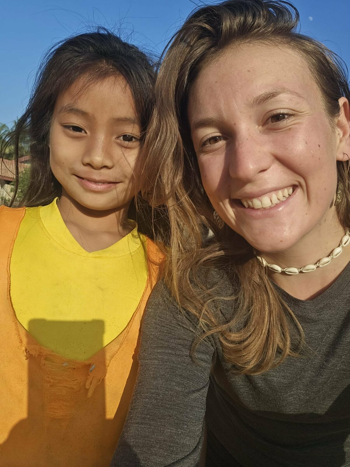 Fanny à gauche souriante et une petite fille à droite, selfie pris sur le vif pendant ses voyages en Irlande et en Asie du Sud-Est. Image qui capture un moment de complicité et de découverte entre voyageuse et enfant rencontrée sur le chemin