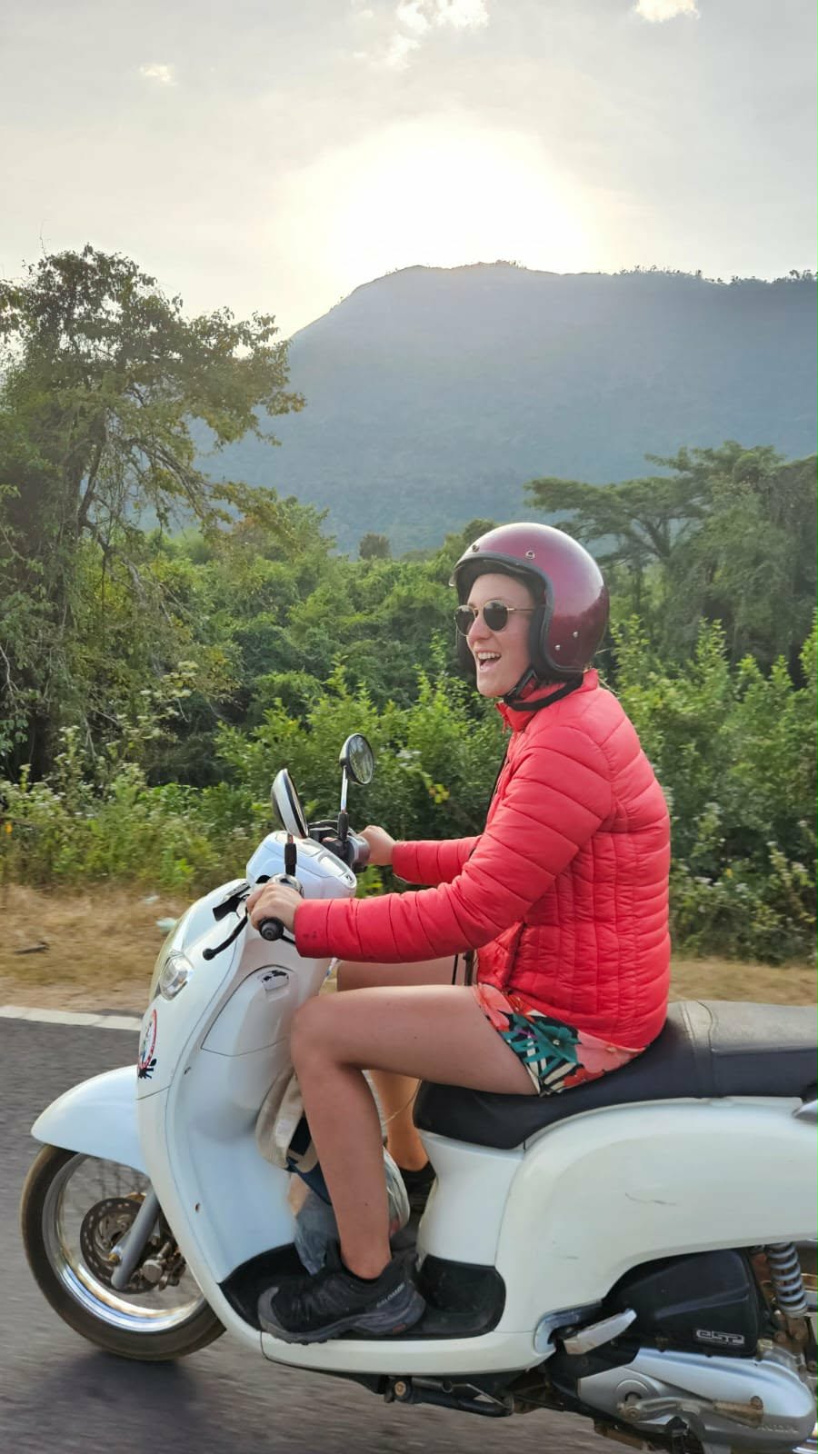 Fanny sur un scooter blanc, parcourant les routes du Laos lors de ses voyages en Irlande et en Asie du Sud-Est. Illustration qui capture la liberté, l’aventure et la découverte des paysages typiques du Laos