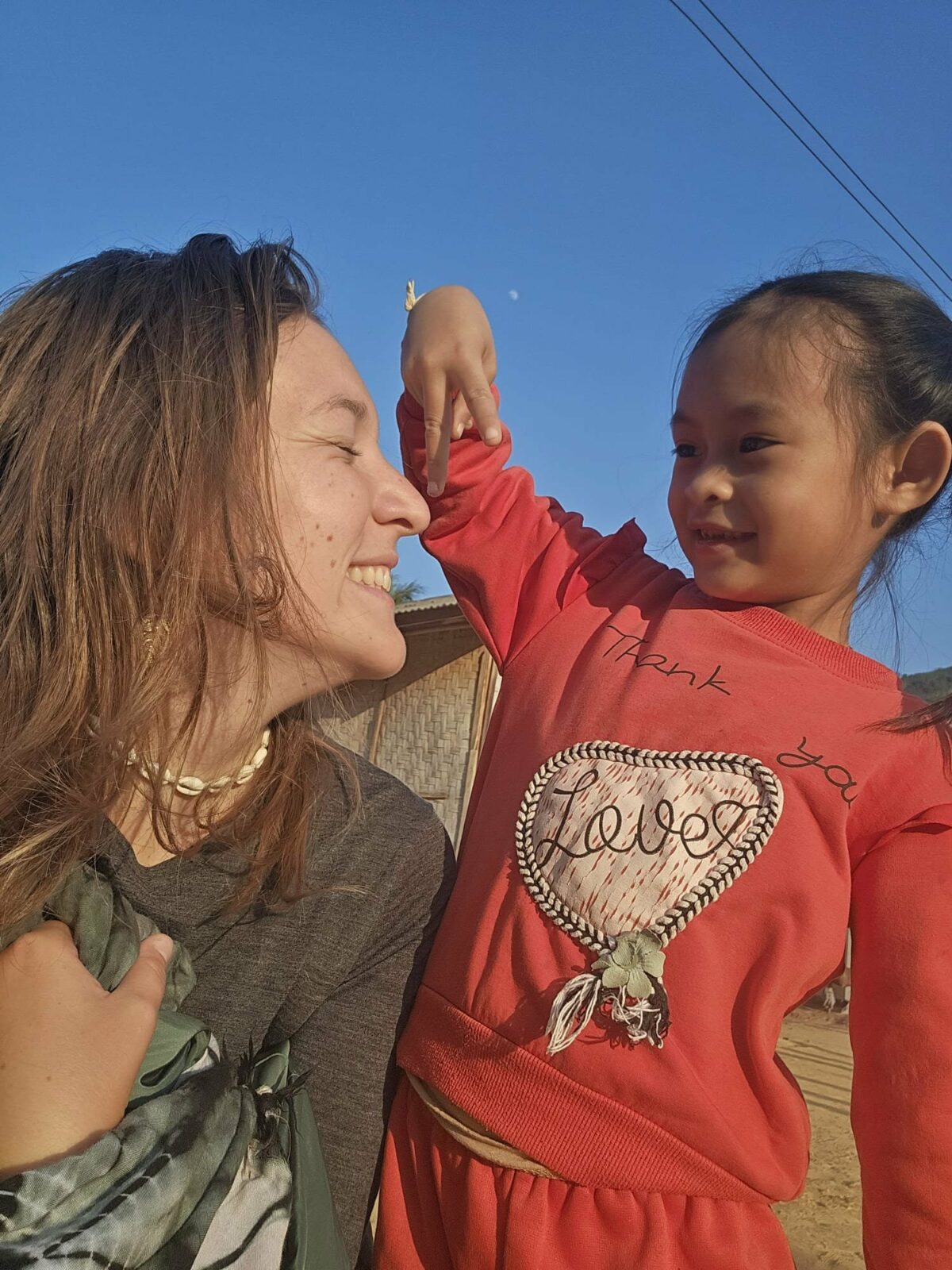 Fanny souriante avec une petite fille rencontrée lors de ses voyages en Irlande et en Asie du Sud-Est. Illustration qui capture la joie, la complicité et la spontanéité des rencontres en voyage solo