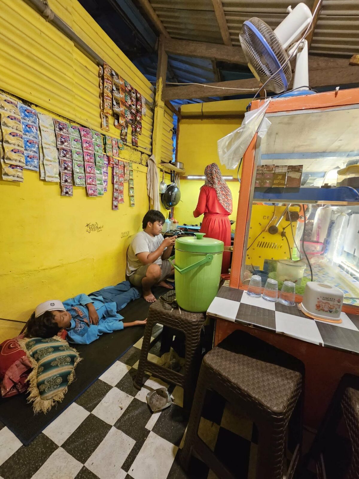 Vendeur de rue avec un enfant assis derrière le comptoir, scène observée par Fanny lors de ses voyages en Irlande et en Asie du Sud-Est. Illustration qui montre la vie quotidienne, les rencontres locales et l’authenticité des marchés