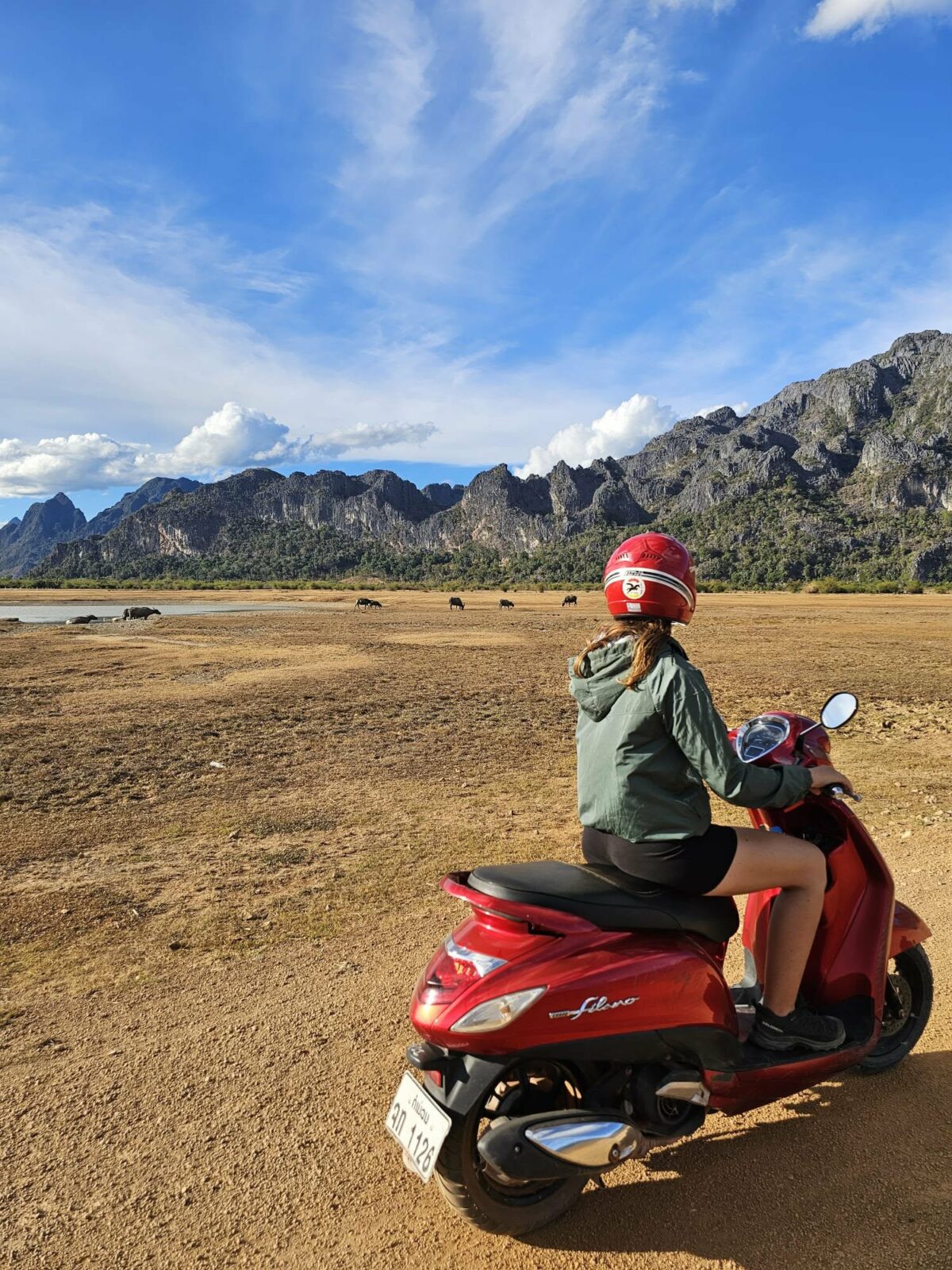 Fanny sur un scooter rouge, parcourant un paysage de montagnes lors de ses voyages en Irlande et en Asie du Sud-Est. Illustration qui capture la liberté, l’aventure et l’exploration des paysages pittoresques
