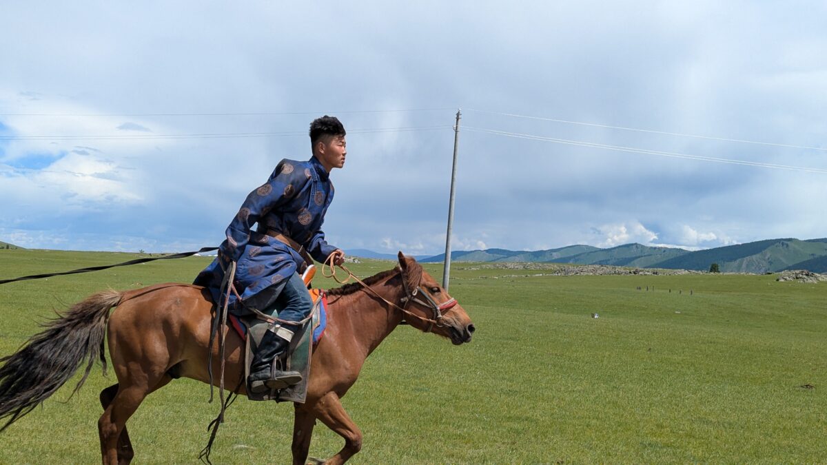 Jeune nomade en Mongolie en plein galop à cheval dans la steppe ouverte. Scène de liberté avec les rênes longues, entre vitesse et vastes paysages