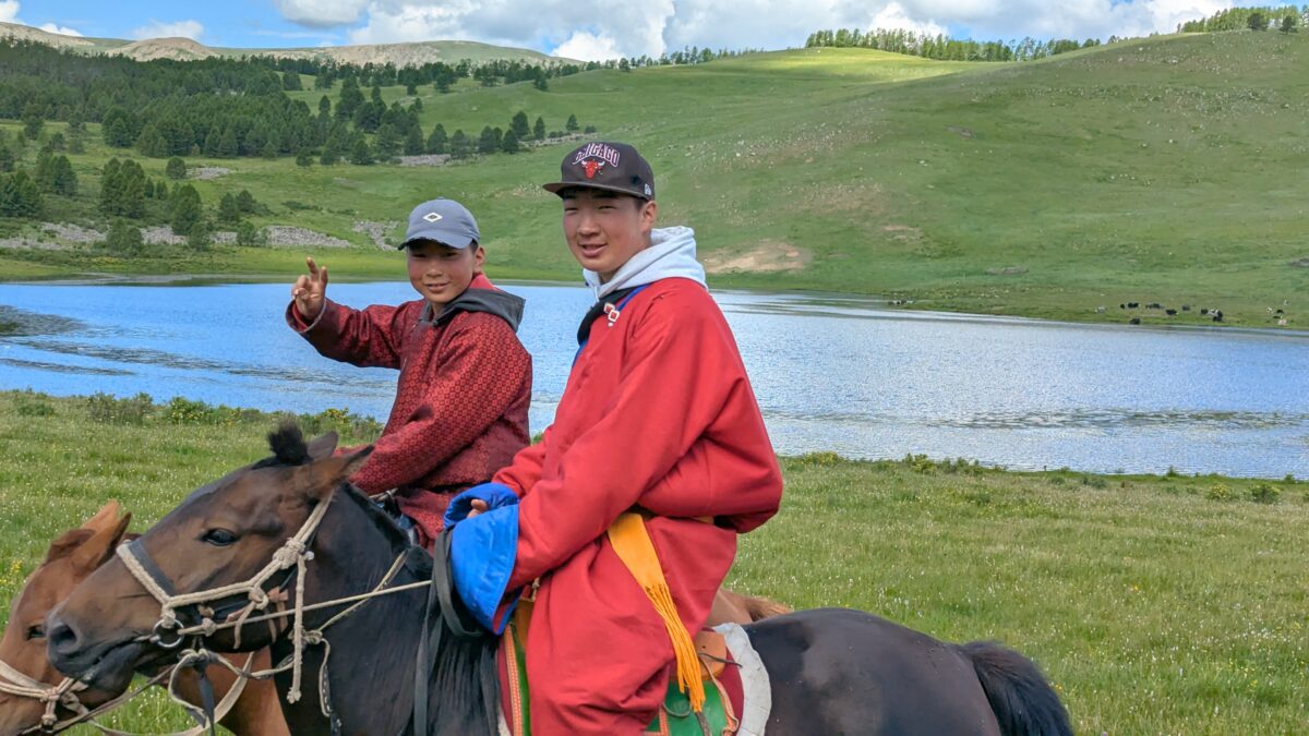 Groupe de jeunes Mongols souriants avec leurs chevaux dans la steppe. Scène de vie nomade joyeuse en Mongolie