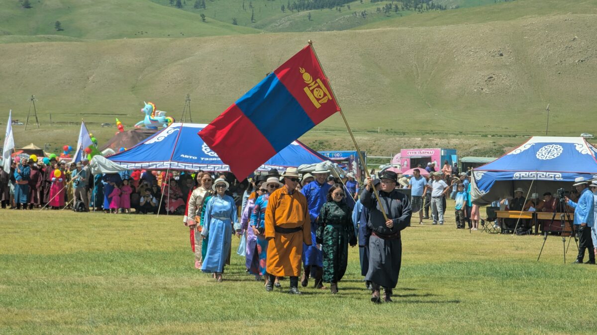 Groupe de participants au Naadam dans la région du Karakorum en Mongolie brandissant le drapeau mongol. Scène festive lors d’un événement traditionnel