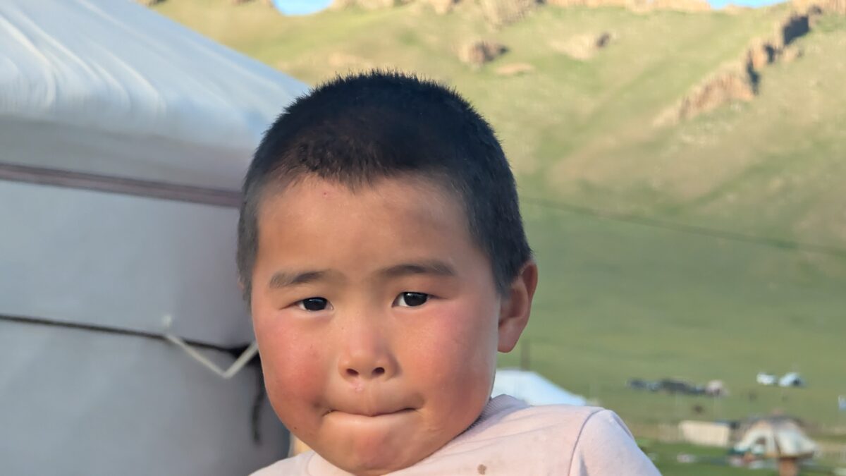 Portrait en gros plan d’un enfant mongol dans la steppe. Yourte visible en arrière-plan