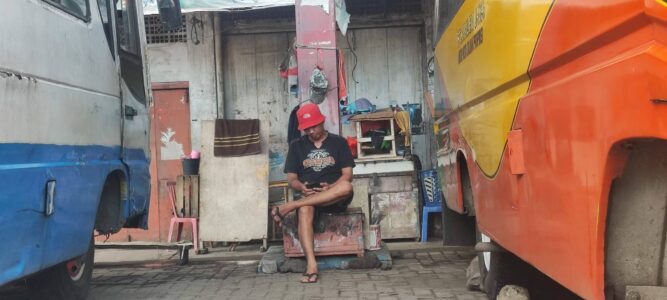Photographie d'un chauffeur assis au milieu des camions de transport collectif bemo à Manado, Sulawesi