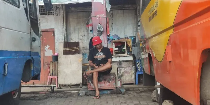 Photographie d'un chauffeur assis au milieu des camions de transport collectif bemo à Manado, Sulawesi