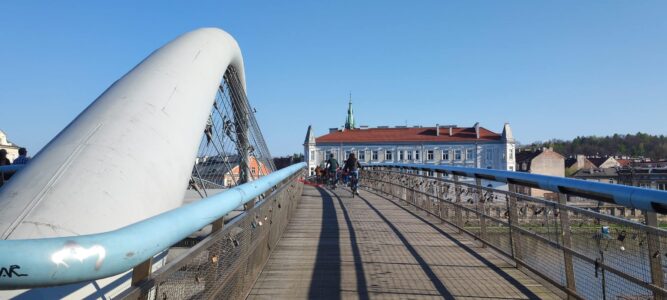 Photographie du Quartier Vistule à Cracovie, montrant un pont au premier plan avec un ciel bleu clair en arrière-plan