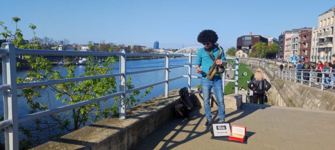 Un musicien joue du saxophone sur les rives de la Vistule à Cracovie, sous un ciel bleu ensoleillé