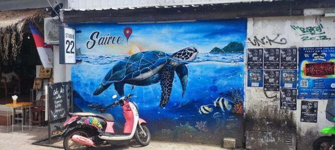 Street art d'une tortue à Koh Tao, avec un scooter rose en arrière-plan