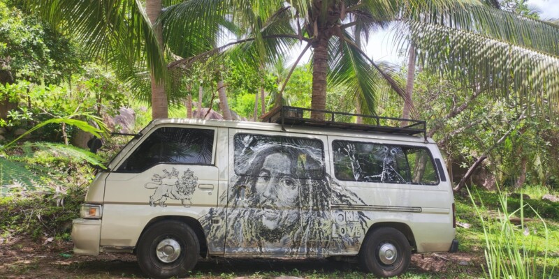Van hippie coloré stationné à Koh Tao, entouré de palmiers