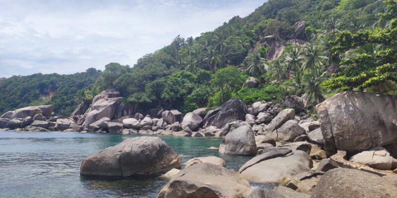 Plage de Koh Tao avec un rocher majestueux, des palmiers et des eaux turquoise