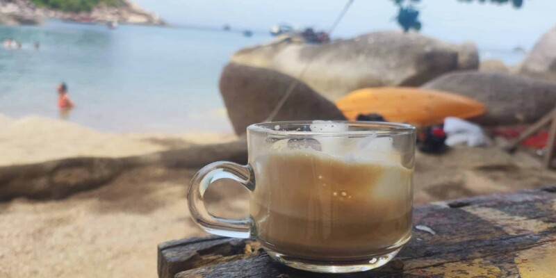 Cappuccino servi dans un café sur la plage de Koh Tao, avec la mer et le sable en arrière-plan