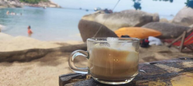Cappuccino servi dans un café sur la plage de Koh Tao, avec la mer et le sable en arrière-plan