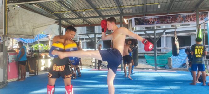 Combat de boxe entre un professeur et un élève dans un camp d'entraînement à Koh Tao, illustrant la passion pour le Muay Thai