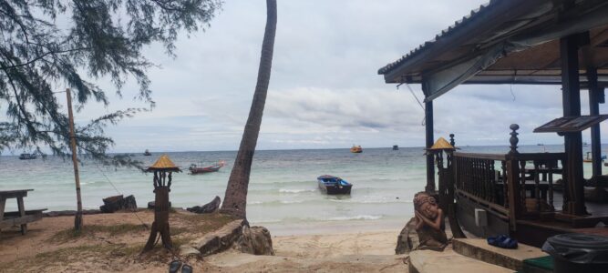 Panorama d'une plage de Koh Tao, avec du sable blanc, des palmiers et des eaux turquoise sous un ciel ensoleillé