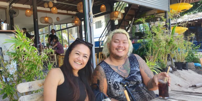 Une femme et un homme thaïlandais souriant joyeusement à Koh Tao, entourés de paysages tropicaux