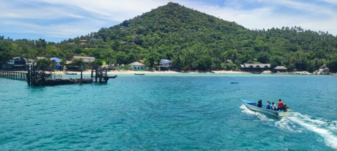 Vue depuis la mer d'une montagne verdoyante à Koh Tao, avec des plongeurs explorant les eaux turquoise