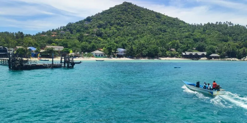 Vue depuis la mer d'une montagne verdoyante à Koh Tao, avec des plongeurs explorant les eaux turquoise