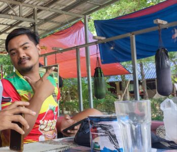 Photographie d'une rencontre avec un boxeur thaïlandais souriant à Koh Tao, faisant le signe de la paix