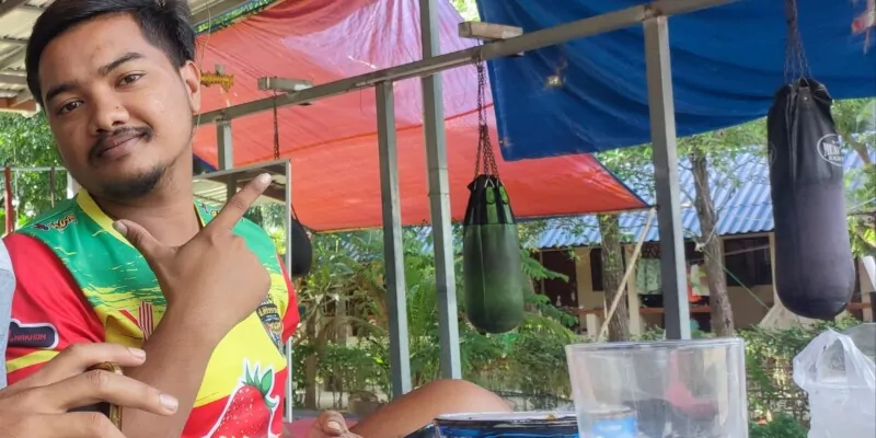 Photographie d'une rencontre avec un boxeur thaïlandais souriant à Koh Tao, faisant le signe de la paix