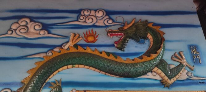 Photographie d'un street art représentant un dragon en relief à Manado, avec un ciel en arrière-plan