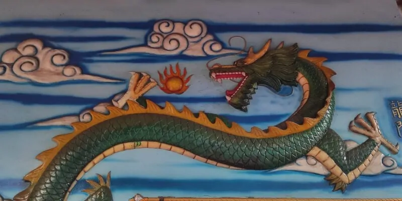 Photographie d'un street art représentant un dragon en relief à Manado, avec un ciel en arrière-plan