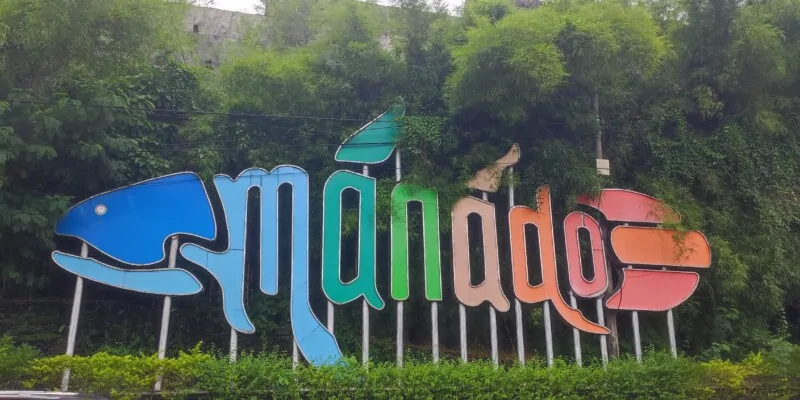 Photographie de la ville de Manado avec le mot "Manado" écrit en motifs de poissons colorés
