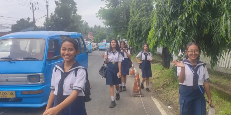 Photographie de cinq étudiantes souriantes à Manado, avec un bemo bleu garé à côté