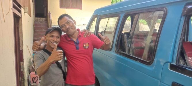 Portrait d'un conducteur de Manado faisant un geste de pouce en l'air à côté d'un bemo bleu
