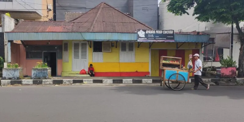Portrait de street food dans une rue de Siau Island, Sulawesi, avec une personne et une maison colorée en arrière-plan