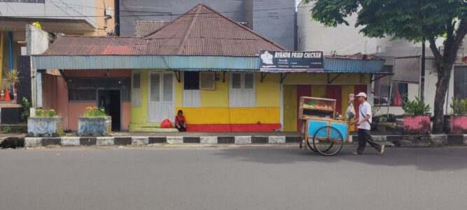 Portrait de street food dans une rue de Siau Island, Sulawesi, avec une personne et une maison colorée en arrière-plan