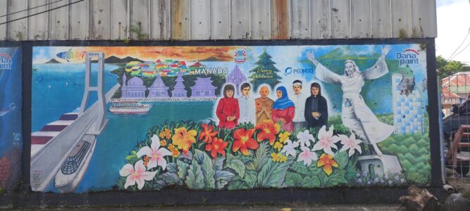 Photographie de street art à Manado, Sulawesi, représentant un pont et la statue du Christ avec la ville colorée en arrière-plan