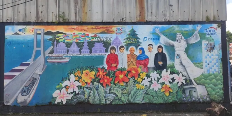 Photographie de street art à Manado, Sulawesi, représentant un pont et la statue du Christ avec la ville colorée en arrière-plan