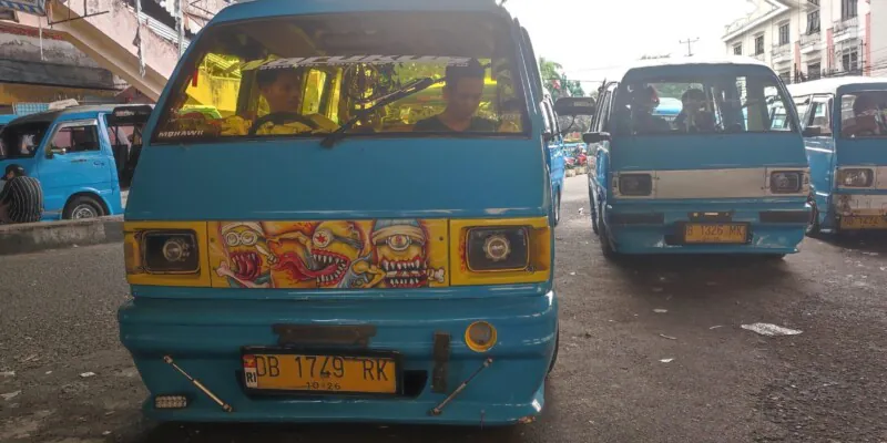 Photographie de bemos bleus à Manado, avec un design de street art et des conducteurs à l'intérieur