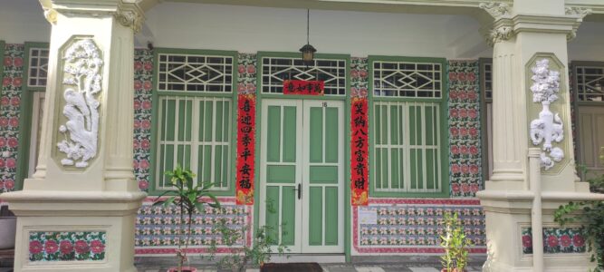 Photographie d'une maison coloniale à Singapour, ornée de détails chics en vert et rouge