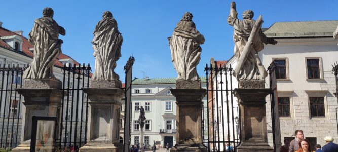 Façade d'une église dans la Vieille Ville de Cracovie, ornée de quatre statues devant un ciel bleu