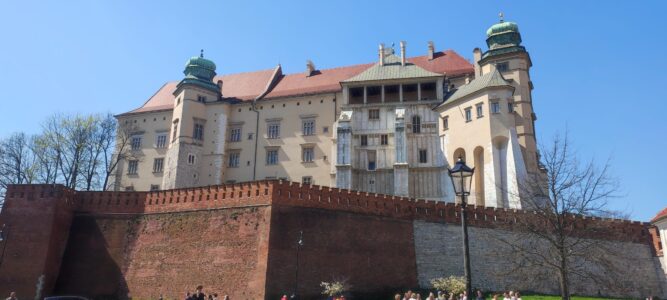 Le Château de Wawel à Cracovie, avec ses tours et murailles en pierre, sous un ciel bleu dégagé