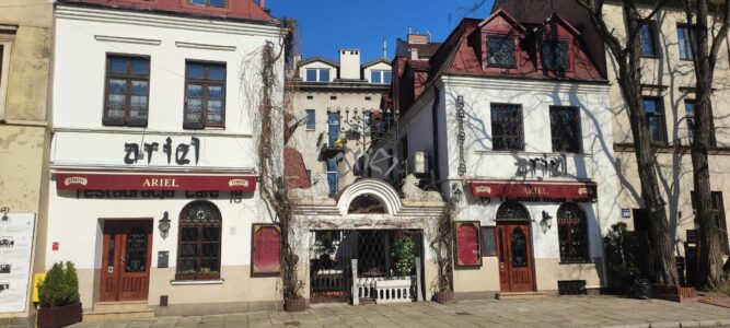 Deux façades blanches avec des rideaux rouges dans le quartier juif de Cracovie, capturées sous un angle en contre-plongée