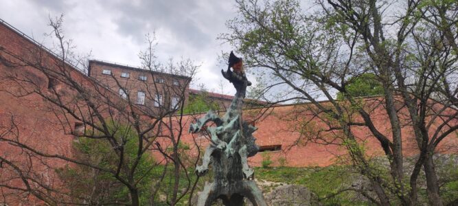 Le Dragon de Wawel à Cracovie crachant du feu près du Château de Wawel sous un ciel bleu