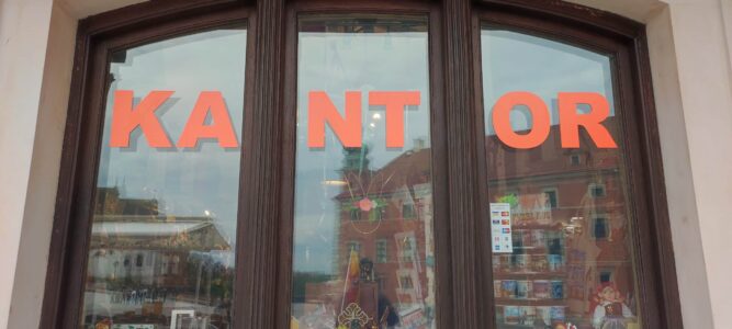 Photographie des vitres d'un bâtiment à Varsovie avec des lettres orange