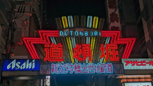 Dotonbori à Osaka la nuit, illuminé par des néons et des enseignes emblématiques le long du canal, offrant une ambiance festive et colorée